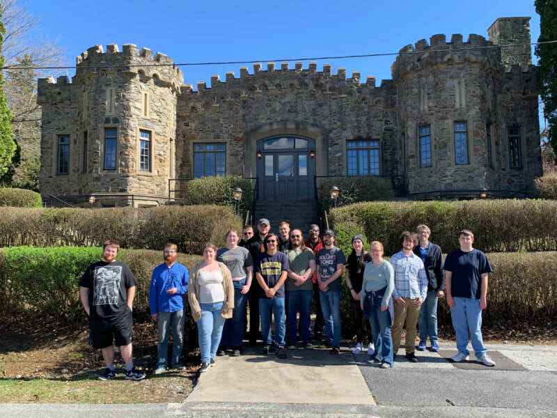 Students and professor from history class standing in front of stone building at Fort Ritchie.
