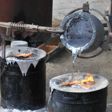 Photo of hot metal being poured from bucket.