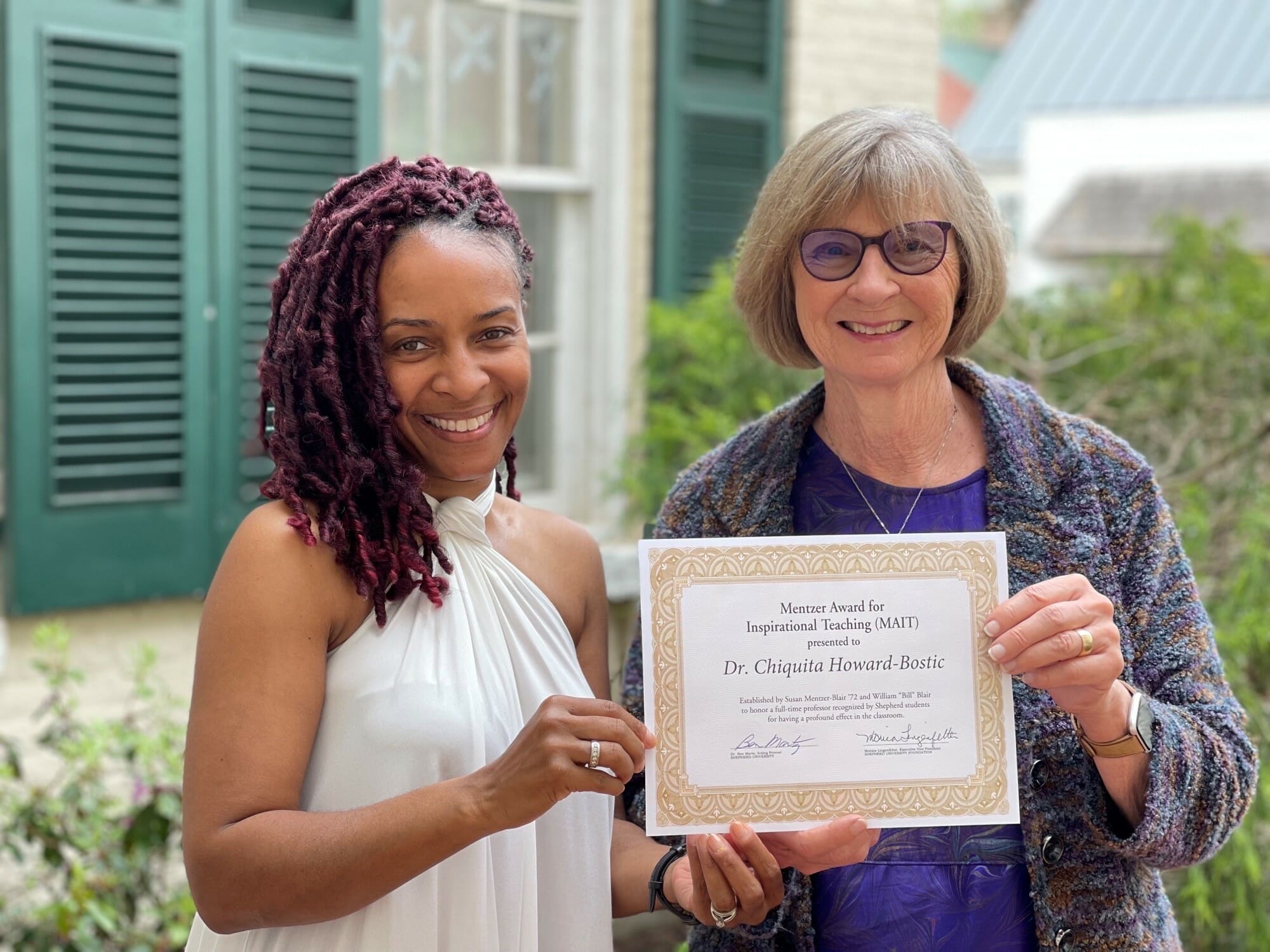 Photo of Dr. Chiquita Howard-Bostic and Sue Mentzer Blair smiling, looking at camera, holding certificate.