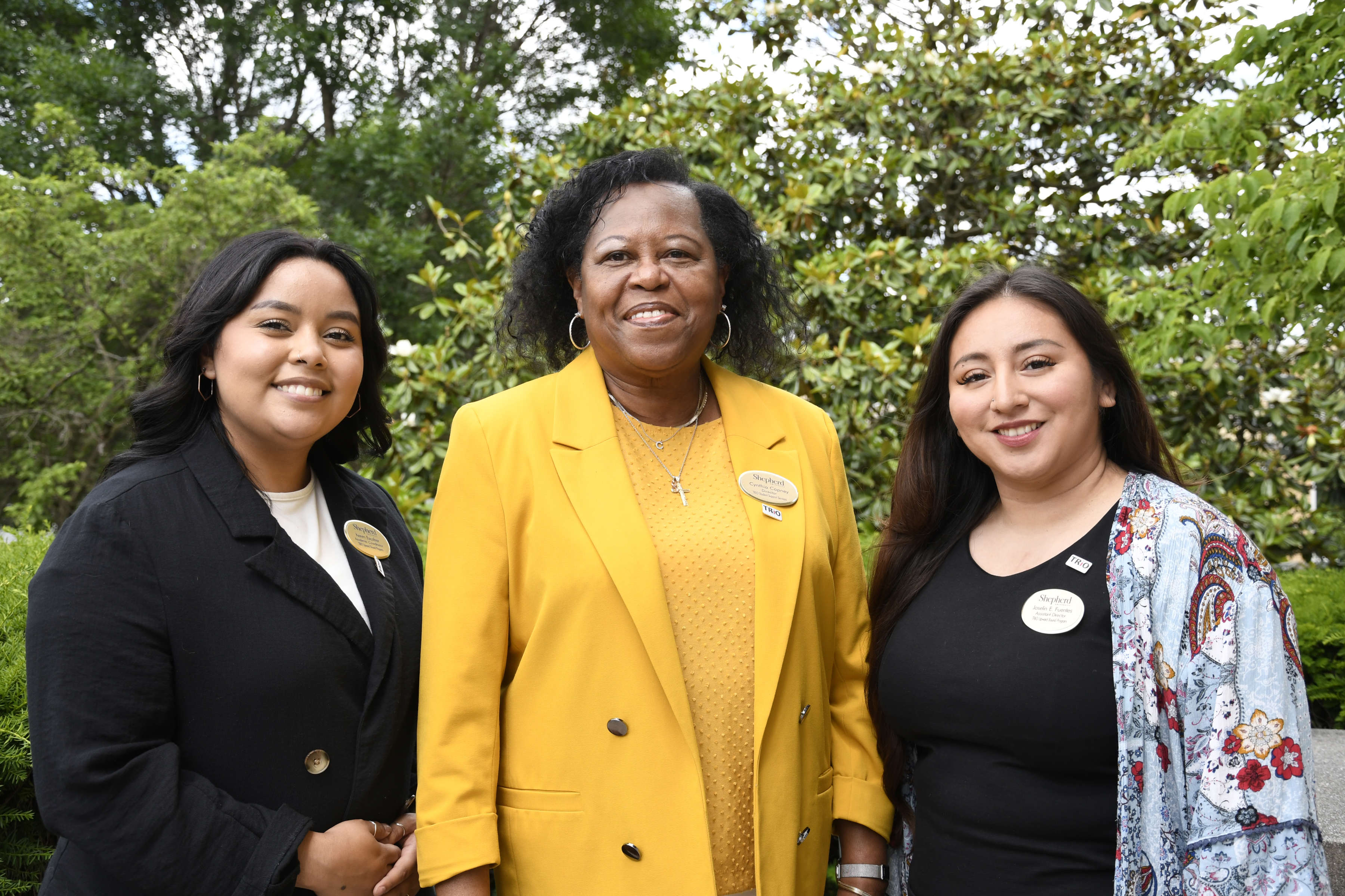 Photo of Karen Escobar, Cynthia Copney, and Joselin Fuentes smiling, looking at camera, in front of greenery