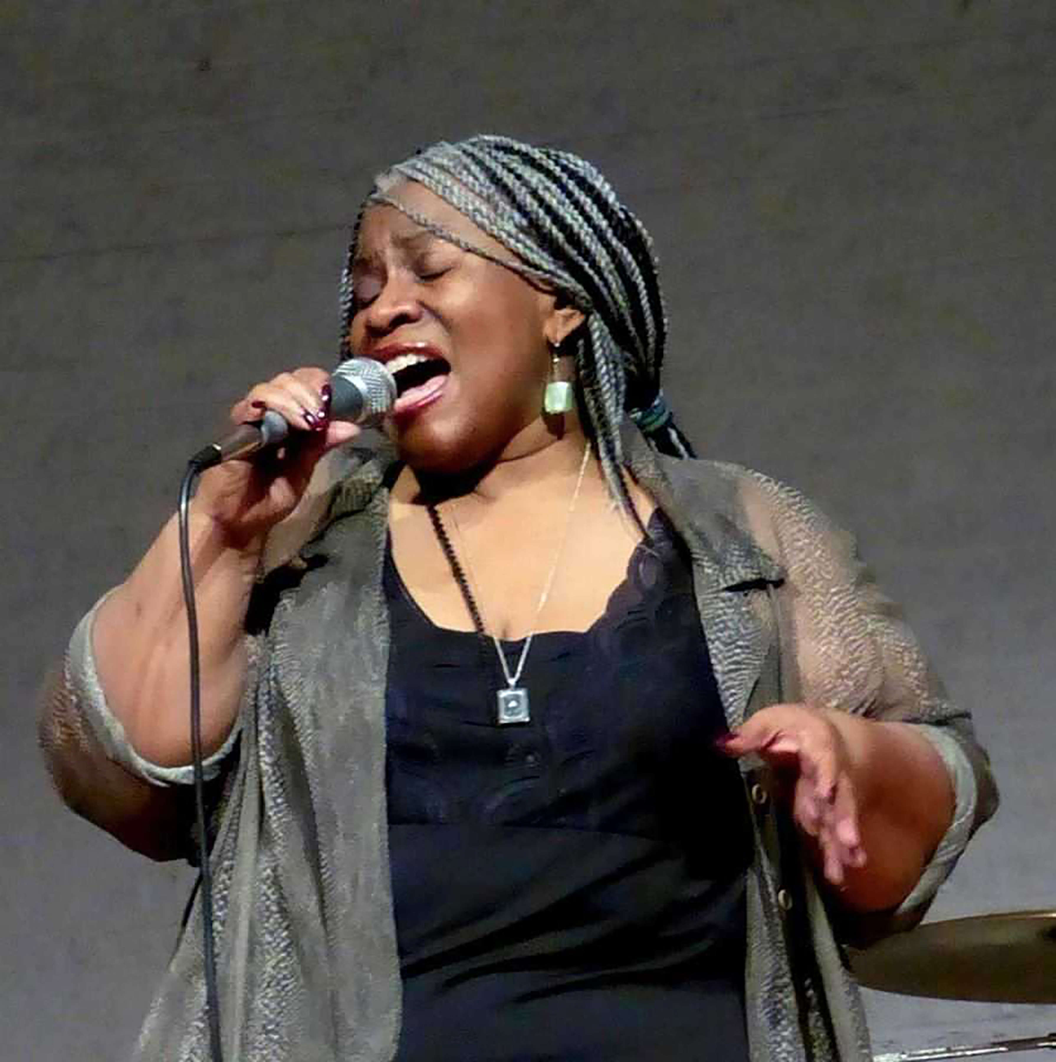 Photo of Lady D singing and holding a microphone.