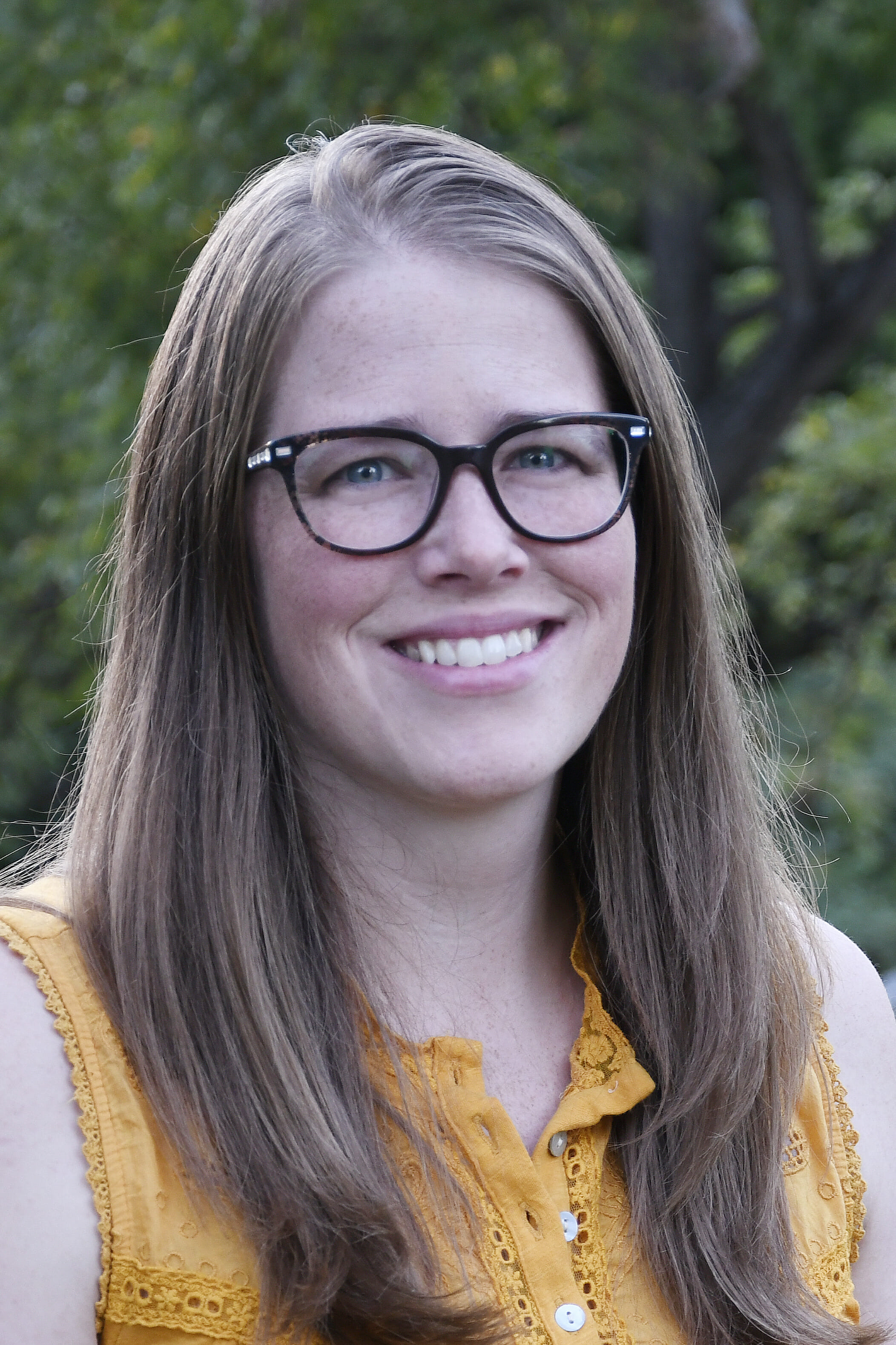 Headshot of Ashley Horst smiling and looking at the camera wearing glasses.