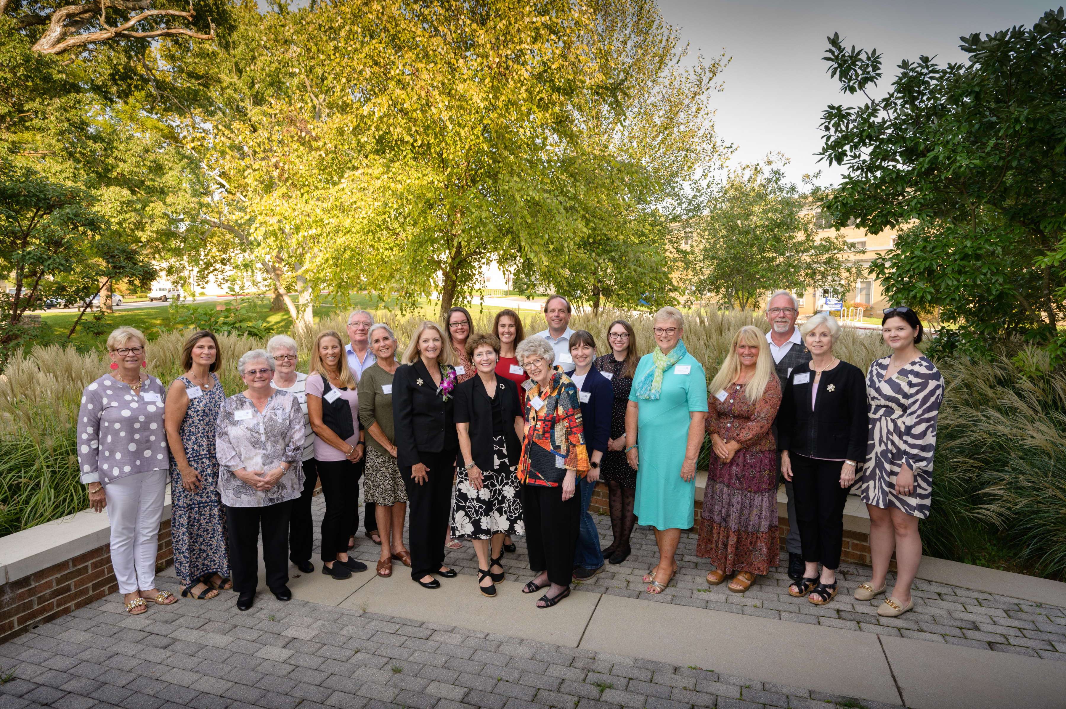 Group photo of WISH grant recipients standing outside the nursing building on a sunny day.