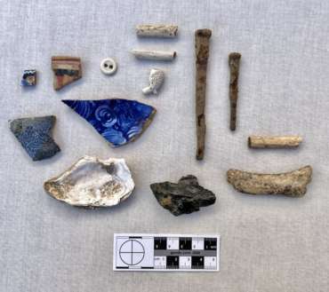 Artifact assemblage excavated from the Shindler House backyard, including nails, ceramics, food items, and clay pipe fragments