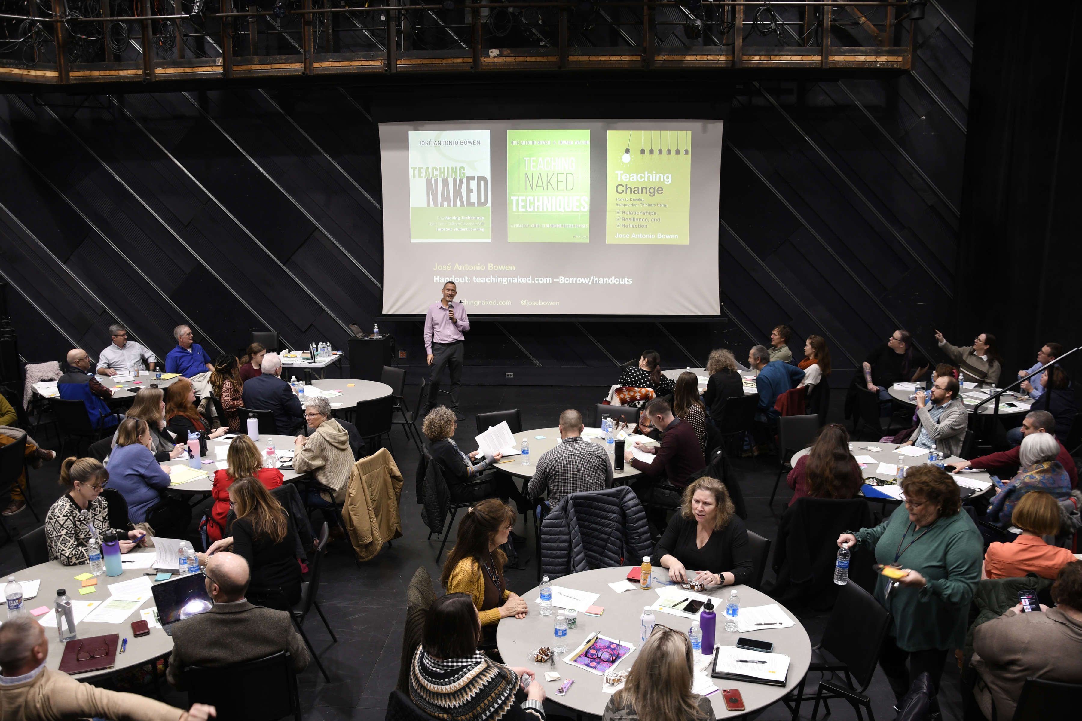 Wide shot of Jose Bowen talking to a room full of professors sitting at tables.
