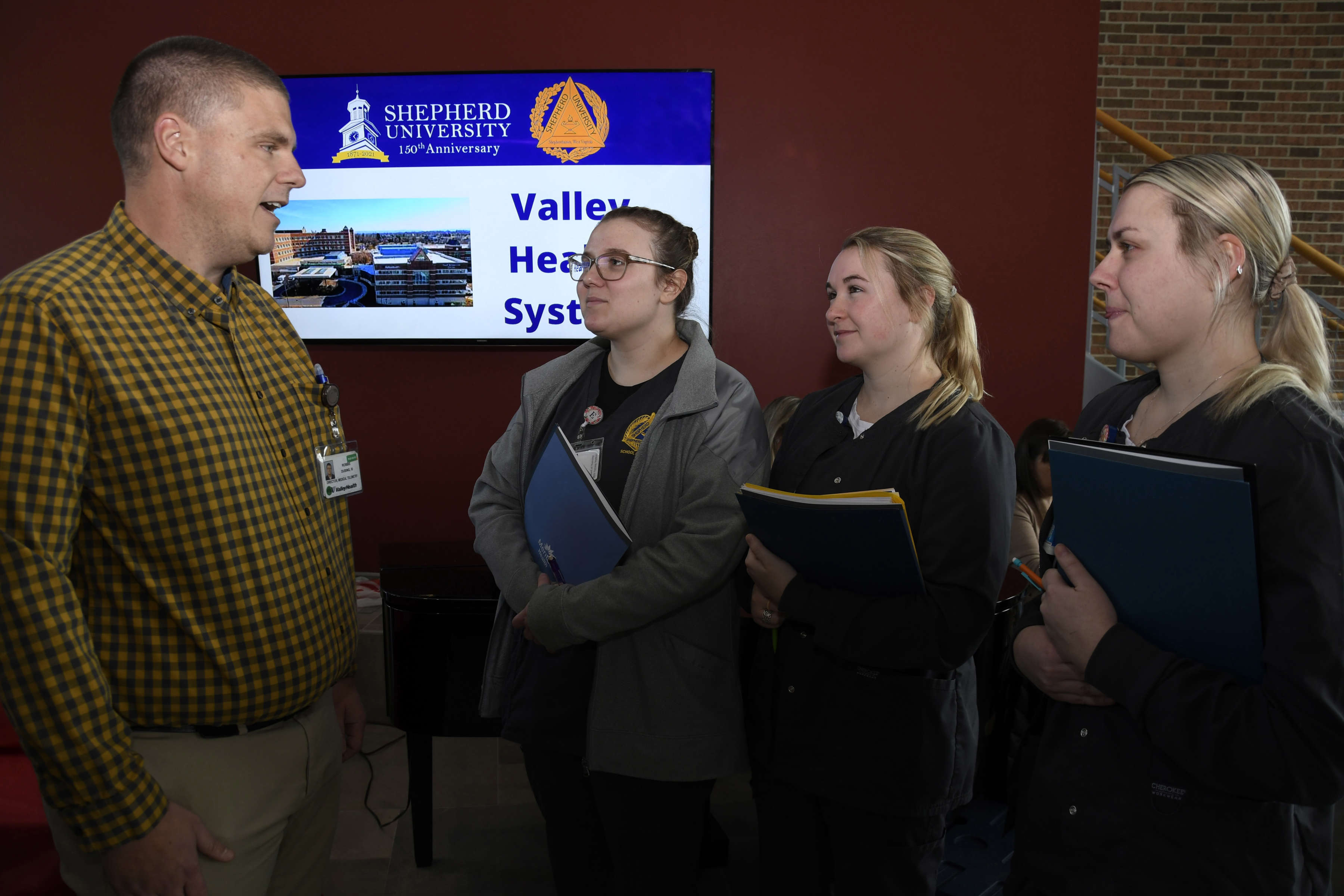 Photo of three students talking to an employee of Valley Health.