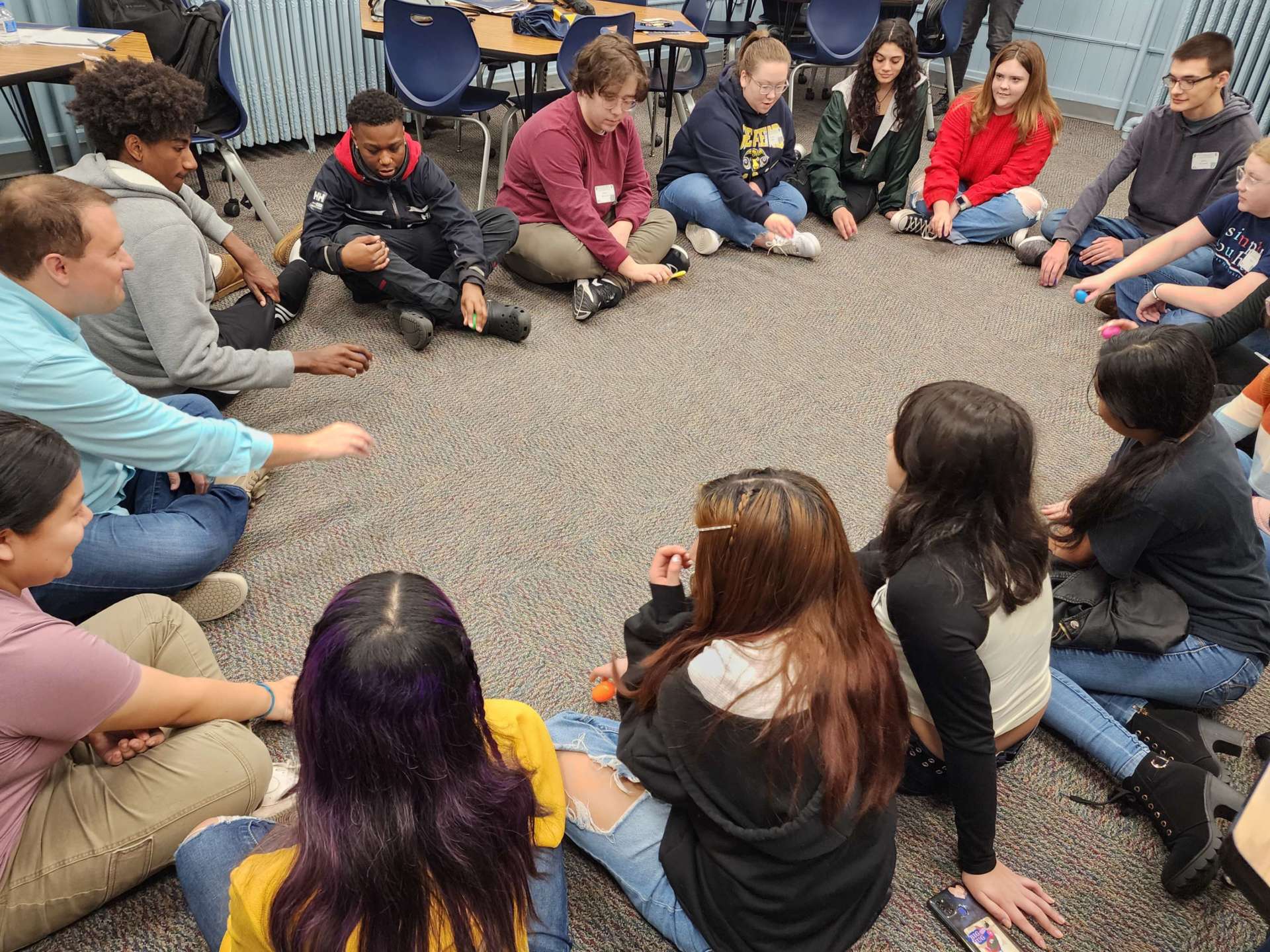 High school students in a classroom sitting on the floor in a circle attending School of Education open house.