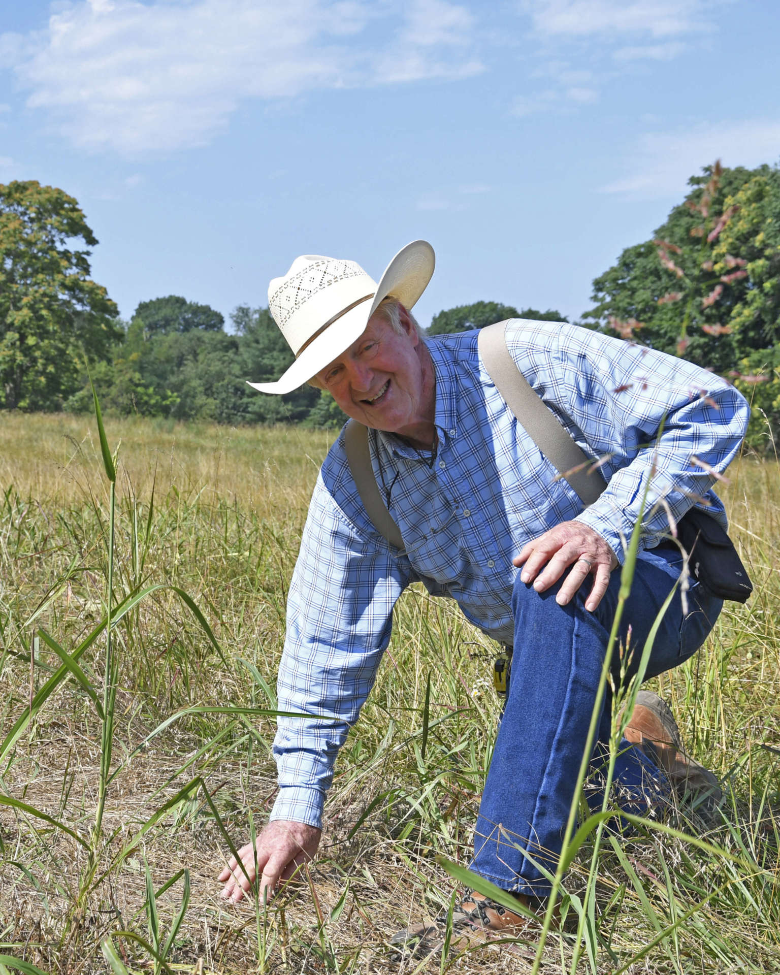 Paul Wilmoth kneeling in the incubator field showing vegetation planted to help rejuvinate the soil.