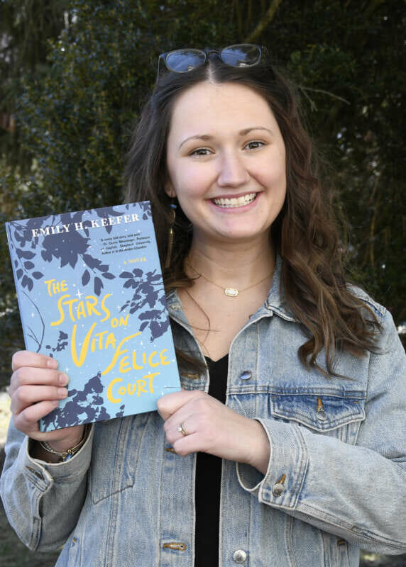 Photo of Emily Keefer holding her book The Stars on Vital Felice Court.