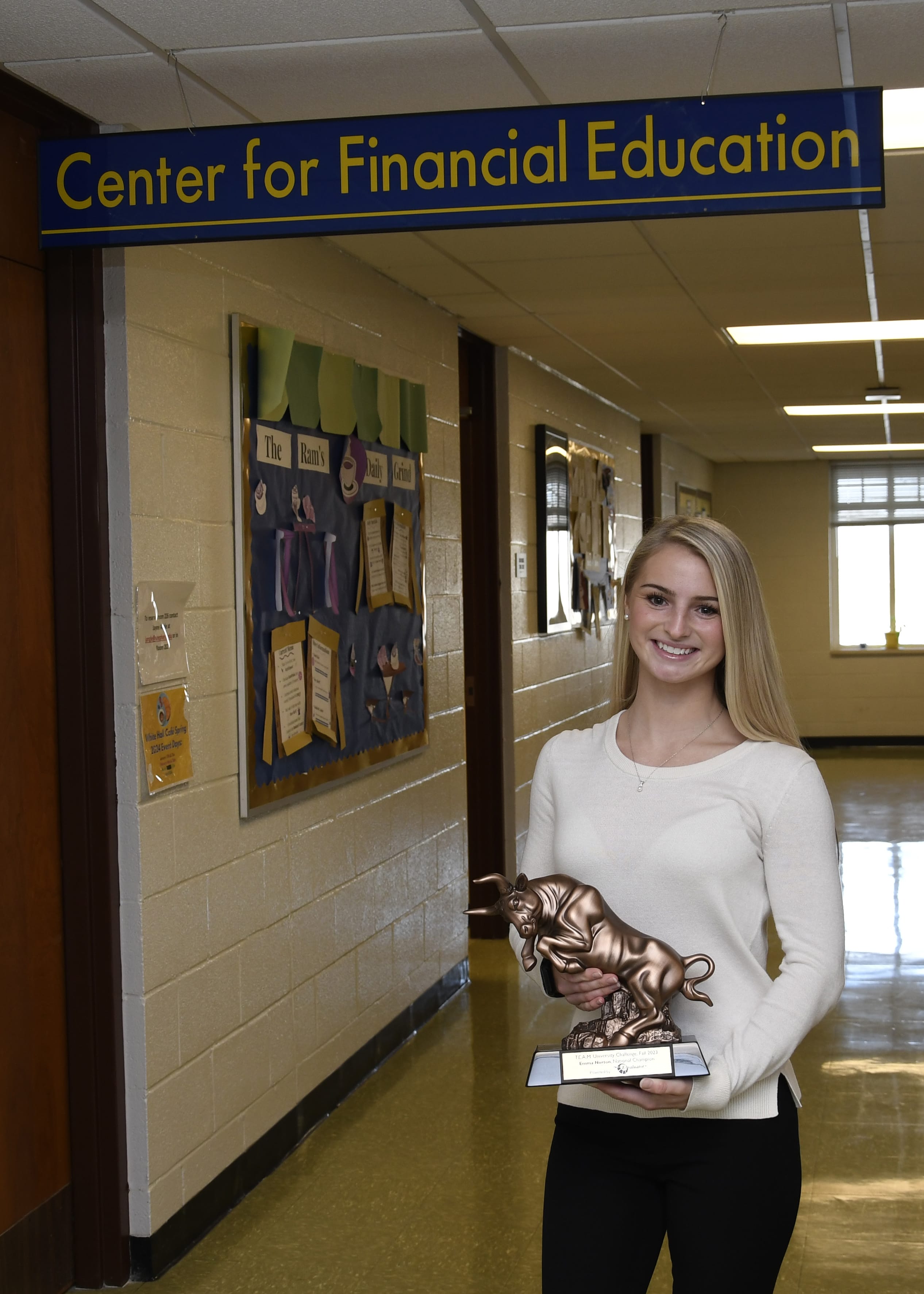 Emma Norton standing in hallway of White Hall holding her trophy that has a bull on it.