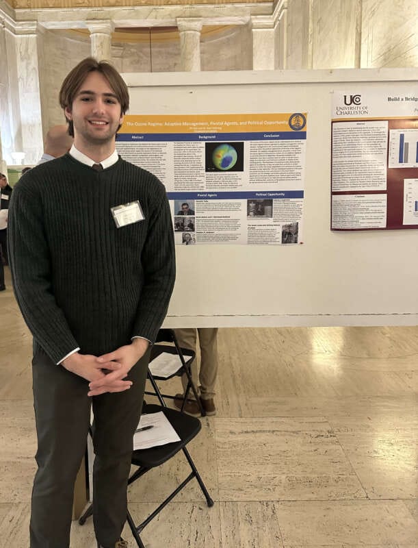 Photo of Eli Hall standing in front of his display during research day at the West Virginia Capitol.