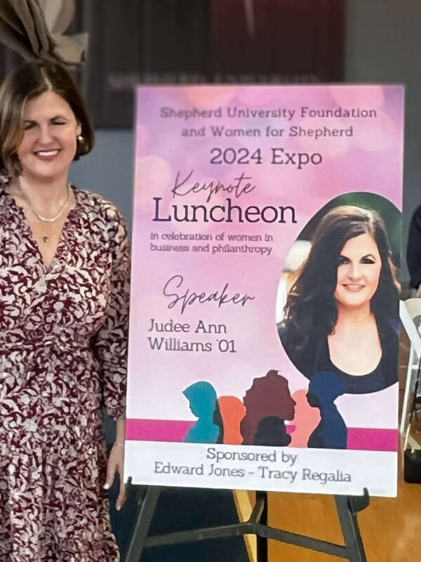 Photo of the women's expo speaker standing next to the poster about the expo.