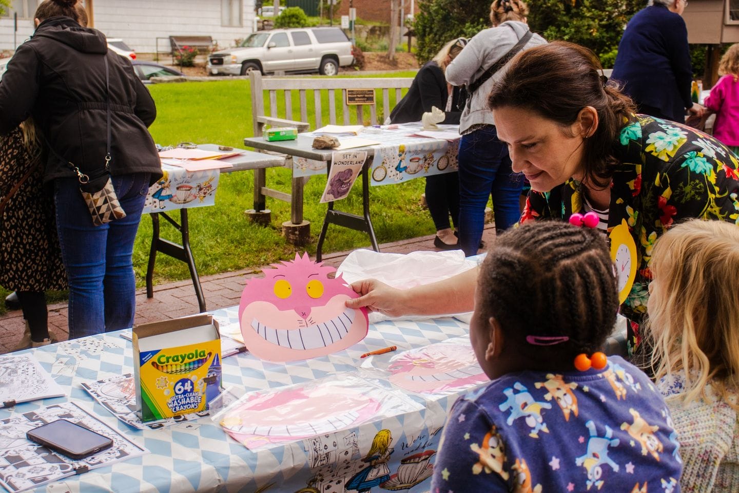 Elementary school students participate in a Cheshire Cat-themed activity on the McMurran Hall lawn.