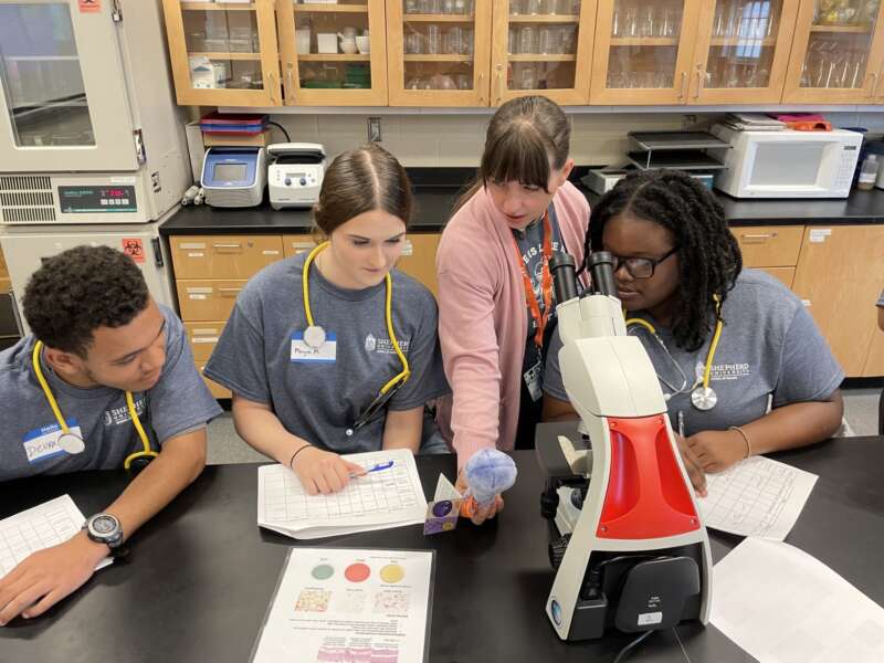 students around microscope at lab table