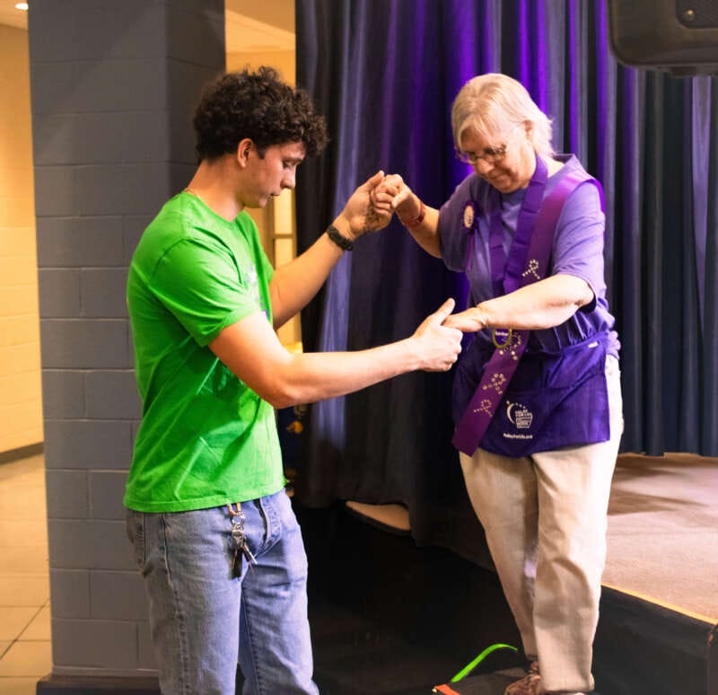 Man in green shirt helping a cancer survivor down the stairs